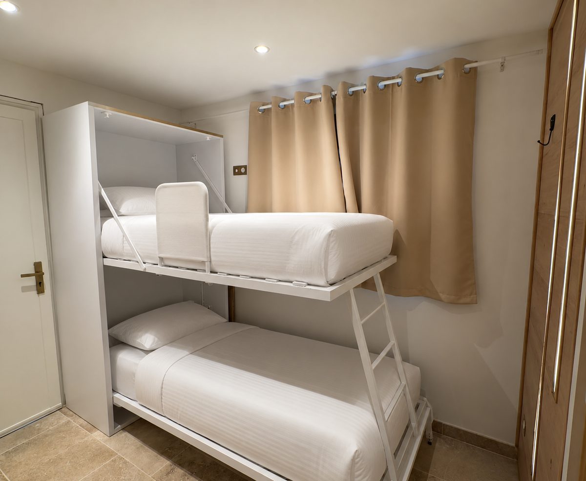 Lits superposés escamotables du studio, habillés de linge blanc, à La Clusaz